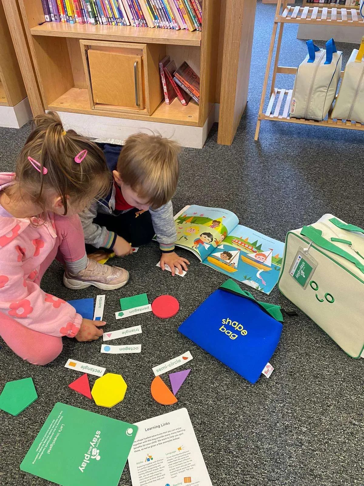 A parent and child playing with wooden toys on the floor