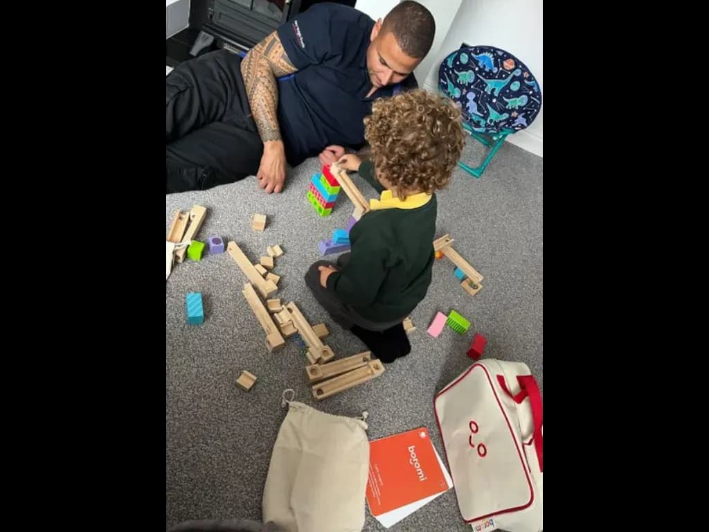 An adult and child building with wooden blocks from a play bag